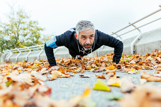 Man doing pushups surrounded by autumn leaves