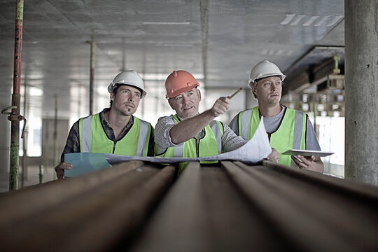 Male construction worker discussing plan with coworkers at construction site