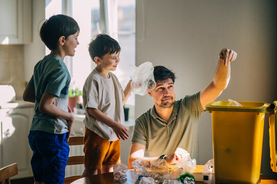 Father and family sorting plastic waste into a bin at home
