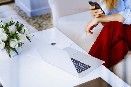 Business professional using smartphone and laptop in modern office