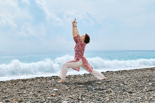 Yogi practicing yoga on a pebble beach by the ocean