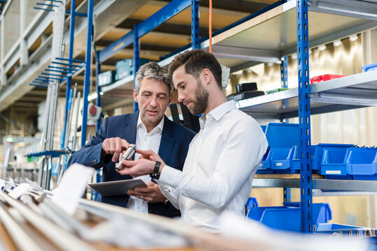 Businessmen during meeting with tablet and product in production hall
