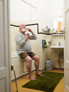 Santa Claus sitting in bathroom drying his beard with a hair dryer