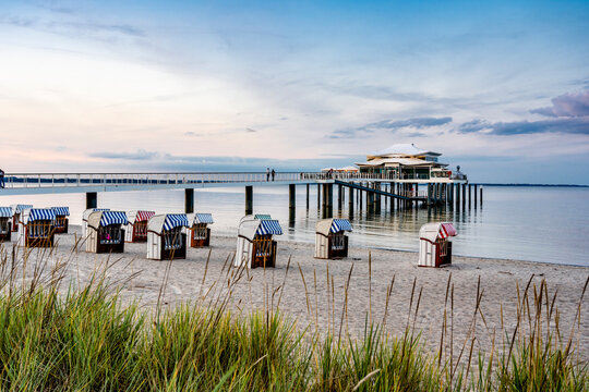 Germany, Schleswig-Holstein, Timmendorfer Strand, Hooded beach chairs with pier and Mikado tea house in background