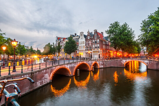 Illuminated bridge over canal in Amsterdam at dusk