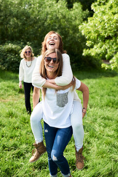 Happy young woman carrying mother piggyback in park