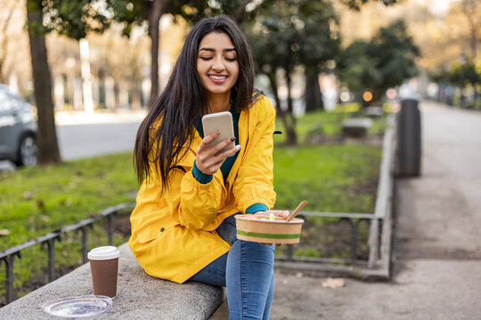 Happy young woman using smart phone on seat
