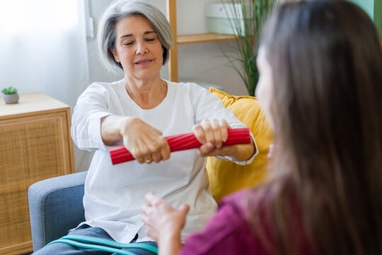 Physical therapist guiding woman during home rehabilitation