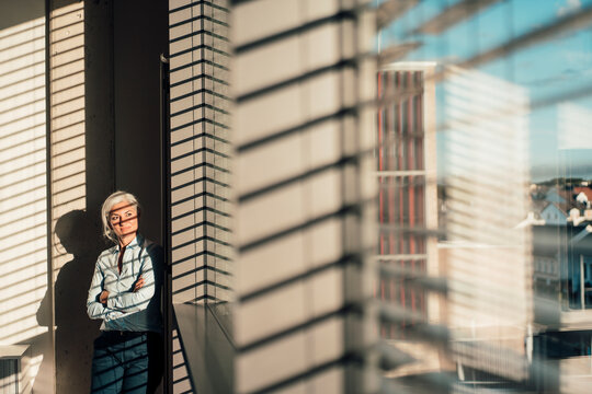 Businesswoman with arms crossed looking through glass window in office