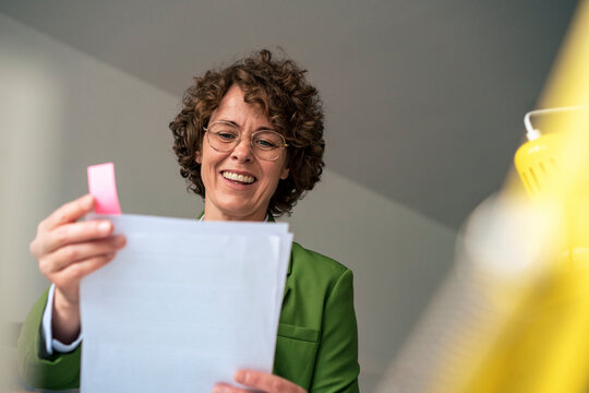 Smiling businesswoman reading document in office