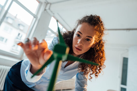 Engineer with curly hair analyzing wind turbine model in office