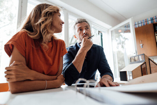 Mature man and woman discussing over real estate contract at table