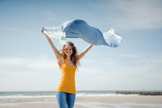 Happy woman having fun at the beach, dancing and swaying towel