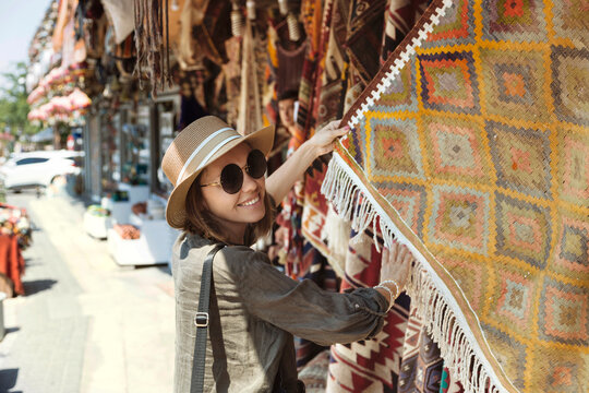 Smiling young woman buying shawl at market stall in Goreme, Cappadocia, Turkey