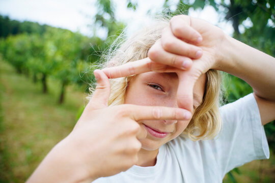 Blond boy showing finger frame sign in garden