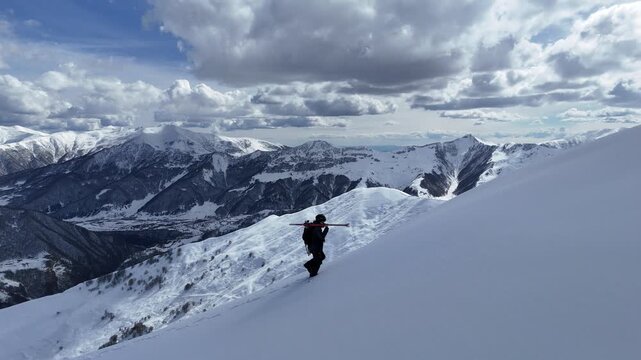 Aerial drone view of a skier hiking up a peak in Gudauri, Georgia. Cinematic minimalist shot of winter mountain freeride filled with zen tranquility.