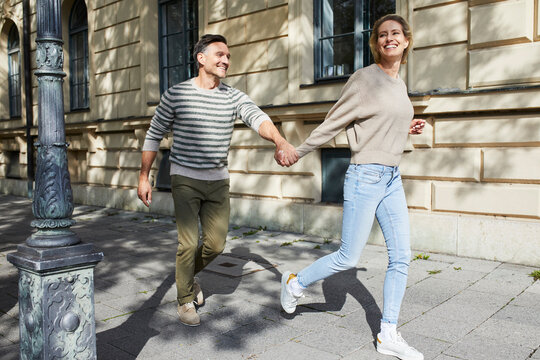 Happy couple running on pavement in the city
