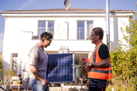 Technician and installer discussing solar panel installation outdoors
