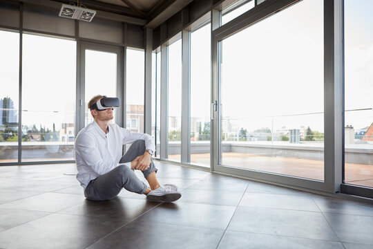Businessman sitting in empty room wearing VR glasses