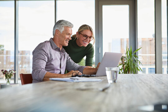 Smiling mature couple using laptop on table at home