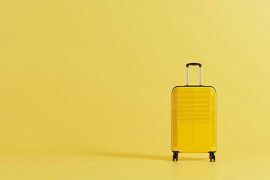 Yellow suitcase standing on yellow background with copy space