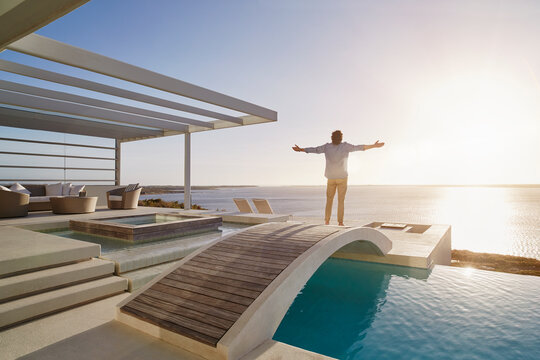 Man standing on bridge above a swimming pool enjoying the view
