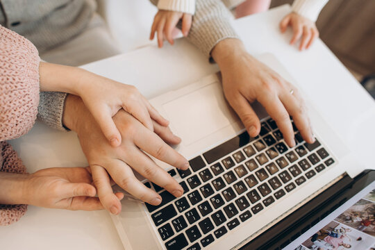 Hands of businessman working on laptop with daughters