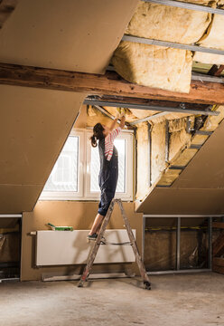 Young woman mounting insulation in her new home