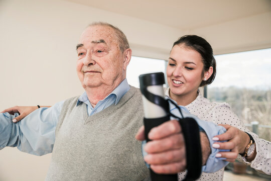 Young woman supporting senior man doing an arm exercise