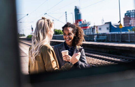 Smiling businesswoman talking to colleague at station platform