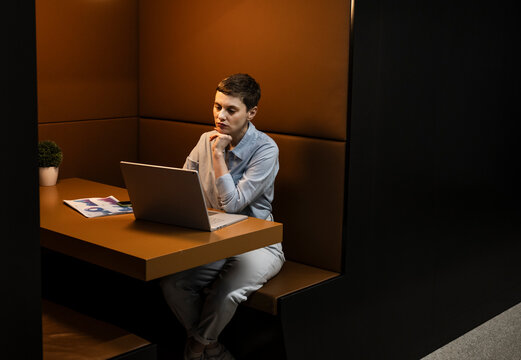 Professional working in modern coworking office booth with laptop