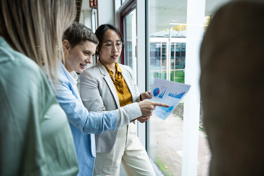 Team discussing business strategy with document in modern office