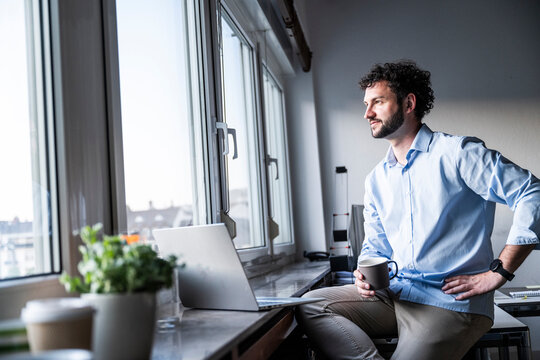 Businessman taking a coffee break and looking out the office window