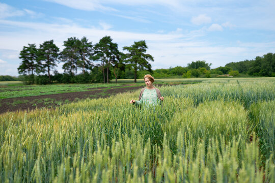Happy woman in vintage dress standing in summer wheat field