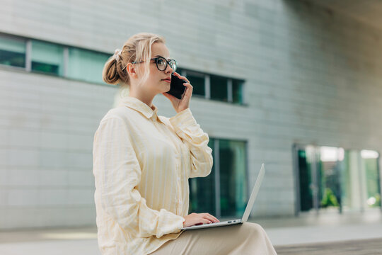 Applicant working on laptop and talking on smartphone outdoors