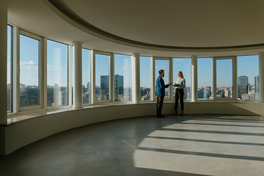 Colleagues discussing business in an empty office with city skyline