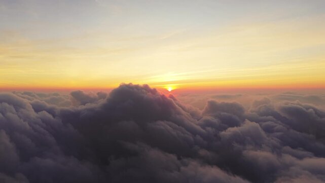 Aerial view of Sindoro Sumbing View featuring thick clouds illuminated by the golden sunset light in Kecamatan Kedu, Jawa Tengah, Indonesia.