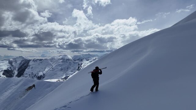 Aerial view of a freerider hiking in deep snow under a bright sun in Gudauri. Ethereal winter landscape bringing clarity and ultimate serenity.