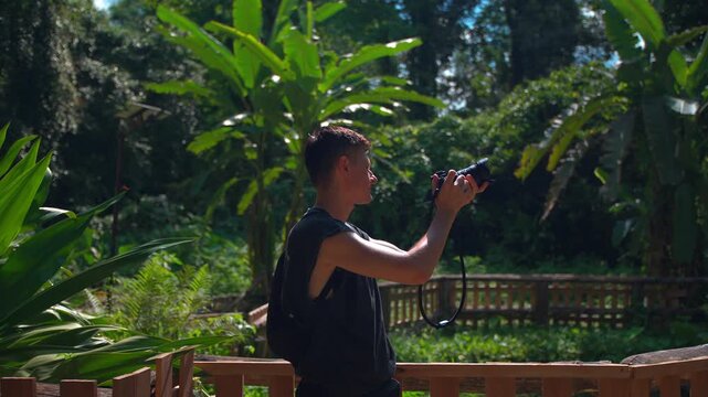 Travel photographer capturing tropical rainforest scenery with professional camera in lush jungle, Man explorer documenting exotic botanical landscapes during ecotourism adventure in Asia 4k
