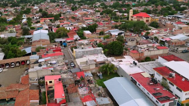 Aerial flyover homes and residential area rooftops toward Capilla San Sebastian church in Tuxpan, Jalisco