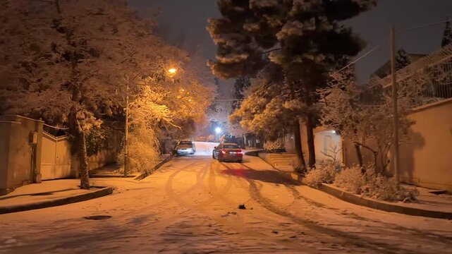Luxury premium sedan automobile vehicle is drifting on icy snowy street in Tehran Iran urban downtown residential area at midnight and headlights traffic in winter storm moody atmosphere safety hazard