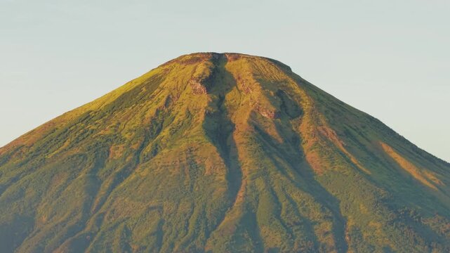 Aerial view of the majestic Mount Sindoro peak rising above a thick layer of morning clouds in Kecamatan Kedu, Jawa Tengah, Indonesia.