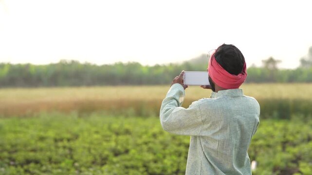 Indian farmer using smartphone at agriculture field 