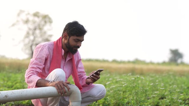 Indian farmer using smartphone at agriculture field 