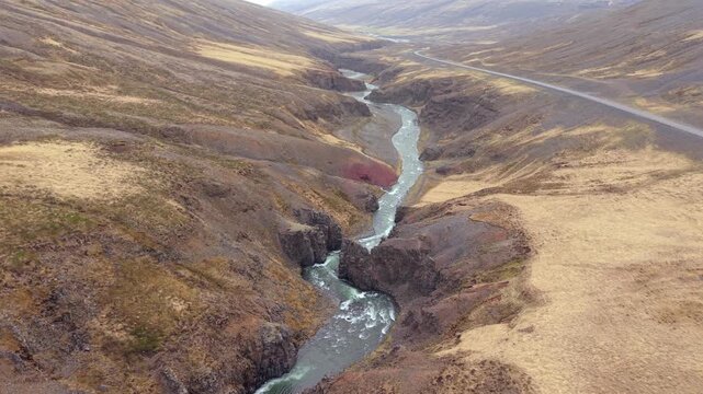 Drone flying over the majestic Nordurardalur canyon with its river flowing through a desolate volcanic valley in Iceland