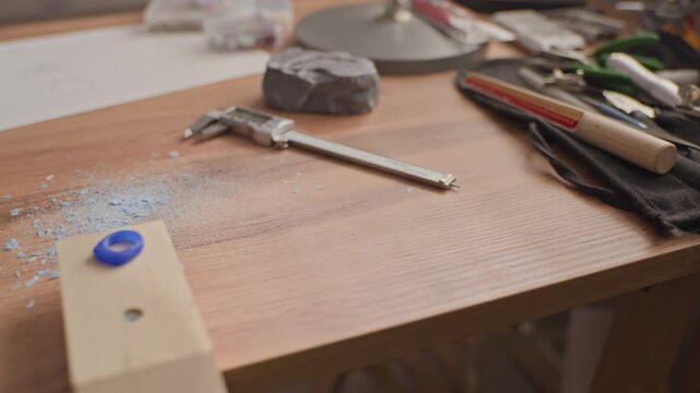 Panning close up shot of jeweler workbench with professional tools, wax ring mold, and finished silver jewelry. Ideal for promoting handmade craft businesses and artisan jewelry brands