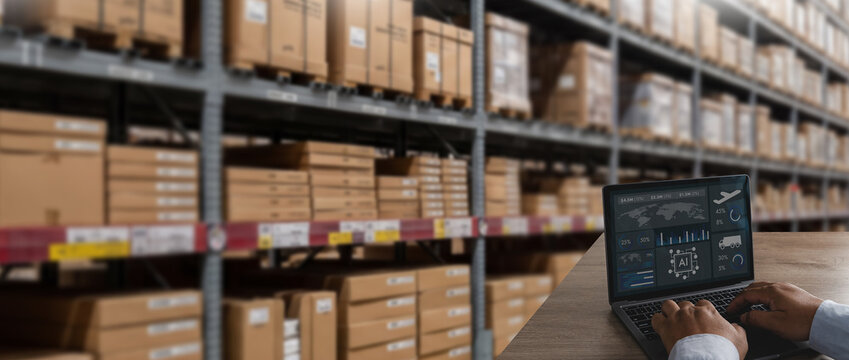 Logistics manager dashboard on a laptop beside warehouse shelves and boxes, analyzing inventory, supply chain, and distribution data for monitoring storage and business operations.