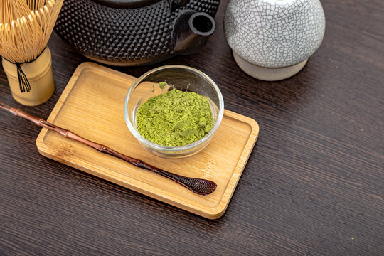 Matcha green tea powder in small glass bowl with bamboo whisk and scoop. Traditional Japanese tea ceremony utensil for preparing healthy organic drink. Calm ritual and relaxation