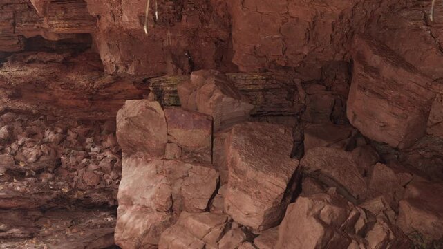 People walk through a cave that has large rocks and walls made of stone. The cave is dark and the atmosphere feels damp and earthy. People check out the various stone shapes and textures.