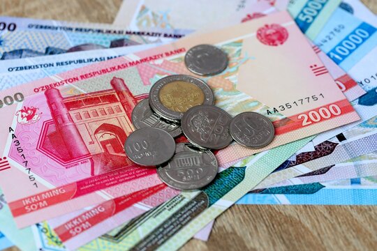 Uzbekistani som money bills and coins on table. Uzbekistan cash of UZS currency close up
